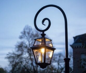 Die Place des Vosges 2 ist eine klassische Gartenlampe aus der Beleuchtungsmanufaktur Roger Pradier, Frankreich. Sie wird in verschiedenen Größen und Ausführungen geliefert. Höhe von 1,50m bis 3,50m. Hier ist die Lampe an einem Bischofsstab aus Aluminiumguss befestigt. Der Lampenmast ist rund und besteht aus Aluminiumguss. Das Oberteil ist in Form eines Bischofstabs. Die Laterne ist viereckig und hat acht Lampengläser.