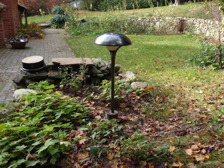 Gartenleuchte mit schwenkbarem Oberteil. Steht in einem Gartenbeet. Hersteller ist LumArt. Sonderfarbe Kanoneneisen.