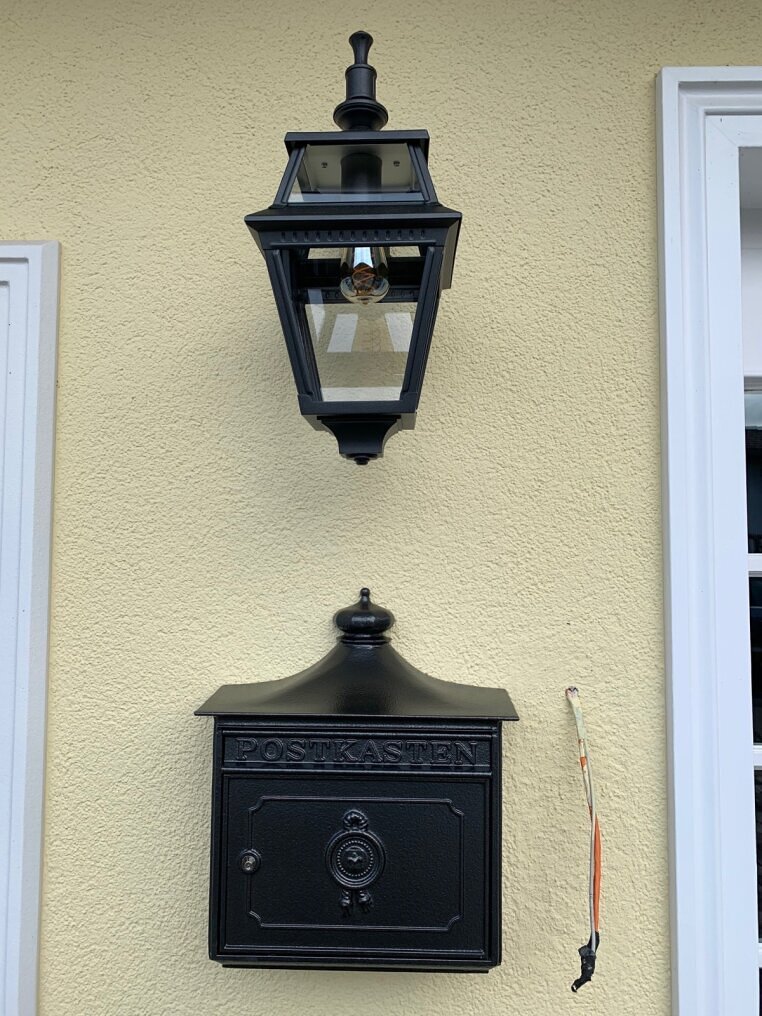 schwarze Wandleuchte hängend an gelber Mauer von Landhaus. PLACE DES VOSGES2 aus Alu, E27, IP44, klasse 1, Klarglas.