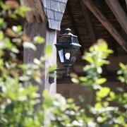 Historische Außenwandleuchte Place des Vosges in Patina-grün mit Klarglas-Scheiben. Vierseitiger Lichtaustritt sorgt für gleichmäßige Ausleuchtung an Hausfassaden mit klassischem Charakter.