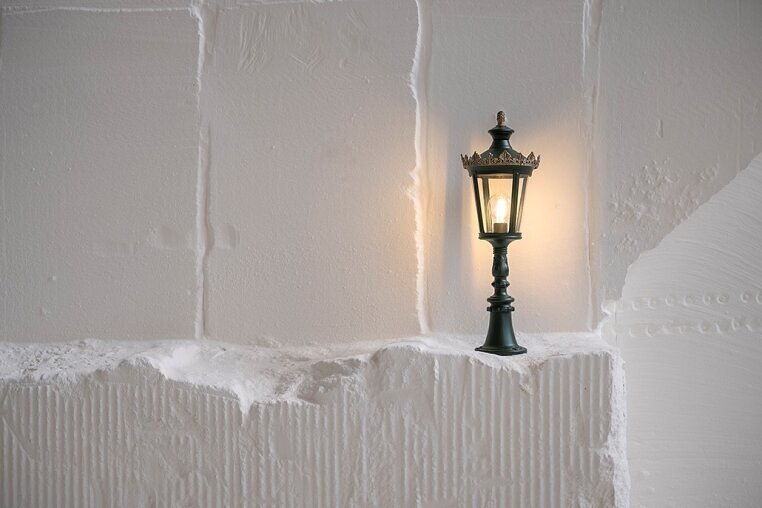 Detailreiche französische Laterne an weißem Putz – stimmungsvolle Lichtwirkung mit authentischem Charme.