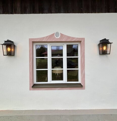 Die Leuchte ergänzt traditionelle Fassadenmalerei und verleiht dem Gebäude zeitlose Eleganz.