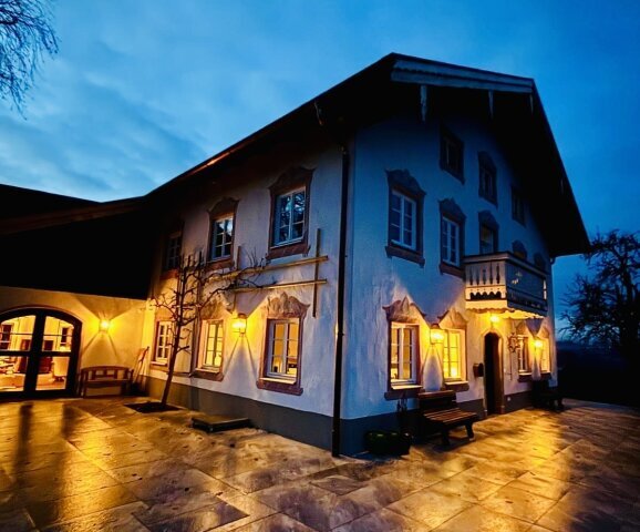 Die Alma 273 in Messing antique setzt elegante Lichtakzente an einer traditionellen Hausfassade im Landhausstil und betont Fenster, Putz und Holzdetails.