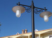 gartenleuchte mediterran. steht in ferienanlage. schmaler mast mit 2 lampenauslegern an jugendstil wandarm. ovale lampengläser.
