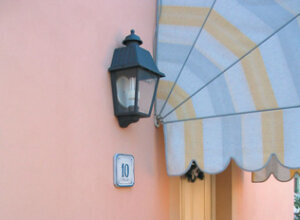 italienische Wandleuchte, flach, Oberteil geschlossen. Glänzender, runder Alu-Reflektor. Farbe: Kupfergrün. An einer rosa Wand von italienischem Landhaus, mediterranes Design.