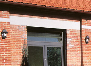 Wandleuchte flache Form mit 6 Klarglasscheiben, schwarz. Sind montiert an roter Ziegelwand, rechte und links eines weißen Fensters.