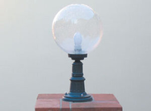 mediterrane Außenleuchte mit Lampenfuß und Glaskugekl auf Mauer.