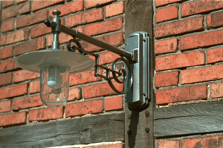 Hoflampe mit Teller an Jugendstilarm. An Fachwerk Hof mit Ziegelsteinen.