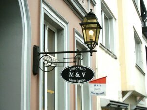 Außenleuchte montiert an einem historischen Haus. Jugendstil Wandarm. Lampe viereckig mit Werbeschild für Außenleuchten.