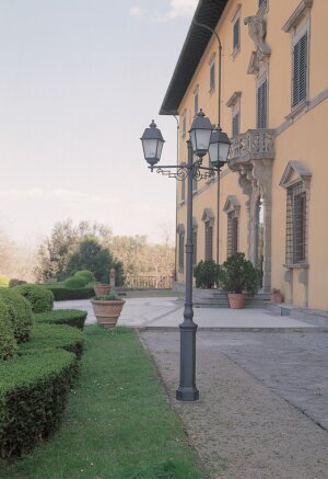 Gartenenleuchte mit drei Lampen im historischen Stil. Steht vor einem Rokoko Schloss.