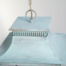 „Nahaufnahme der handgearbeiteten Übergänge und Zierdetails der Pétrole Wandlampe“ Sichtbar ist die grün-weiße Patina und die Deckenbefstigung mit Ring und Kette.