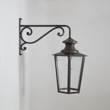 „Außenlampe Vaucresson Nr. 1121 mit Wandarm Nr. 82817 – stilvolle Montageoption für klassische Fassaden“. Seitenansicht mit sechseckiger Lampe unter einem Jugendstilwandarm montiert. Material: Messing antique.