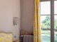 rechteckige Wandleuchte mit klaren Formen in silberem Glanz durch das gebürstete Nickel-Finish. Blick ins Zimmer und auf das Fenster.