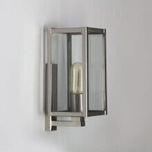 Warmer Lichtschein bei reduzierter Form – stilvoll zurückhaltend. Rechteckiges, klares Gehäuse mit L-förmigen Wandarm, der die Lampe nach oben stützt. Silberner Glaz durch gebürstetes Messing