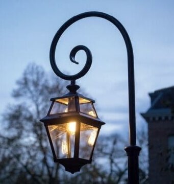 Die Place des Vosges 2 ist eine klassische Gartenlampe aus der Beleuchtungsmanufaktur Roger Pradier, Frankreich. Sie wird in verschiedenen Größen und Ausführungen geliefert. Höhe von 1,50m bis 3,50m. Hier ist die Lampe an einem Bischofsstab aus Aluminiumguss befestigt. Der Lampenmast ist rund und besteht aus Aluminiumguss. Das Oberteil ist in Form eines Bischofstabs. Die Laterne ist viereckig und hat acht Lampengläser.