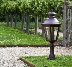 die klassische Gartenbeleuchtung hat ein sechseckiges Gehäuse und steht auf einem kleinen Lampenfuß aus Aluminium. Die sechs Lampengläser schirmen das Leuchtmittel ab.