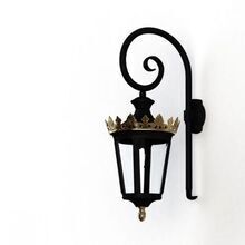 Diese edle Wandlaterne vereint klassische Eleganz mit hochwertiger Verarbeitung. Der dunkle Metallrahmen im Laternenstil wird von einer kunstvoll gestalteten, goldenen Krone gekrönt, die der Leuchte einen königlichen Charakter verleiht. Die geschwungene Wandhalterung aus robustem Material unterstreicht das dekorative Design und sorgt für einen sicheren Halt. Klare Glaseinsätze lassen das Licht der Glühbirne gleichmäßig strahlen und setzen charmante Akzente in jedem Außenbereich. Diese Wandaußenleuchte eignet sich perfekt für historische Fassaden, luxuriöse Eingangsbereiche oder romantische Gartenanlagen. Ihr zeitloses Design macht sie zu einer stilvollen Wahl für gehobene Außenbeleuchtung.