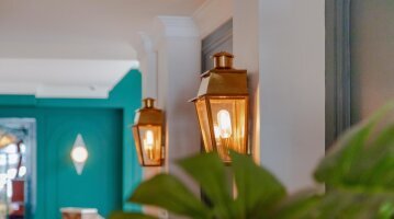 Zwei klassische Wandleuchten aus Messing von LumArt beleuchten eine Haustür in mediterranem Stil. Das warmweiße Licht schafft eine stimmungsvolle Atmosphäre im Eingangsbereich.