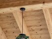 Deckenleuchte für den Aussenbereich. Offenes Lampengehäuse. Hängt an eiener Holzdecke. Lampenfarbe ict grün.